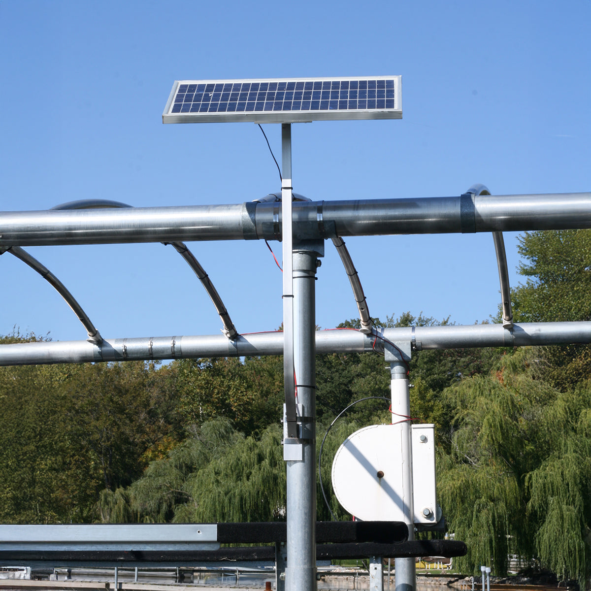 Solar panel on a metal structure with trees and clear sky in the background