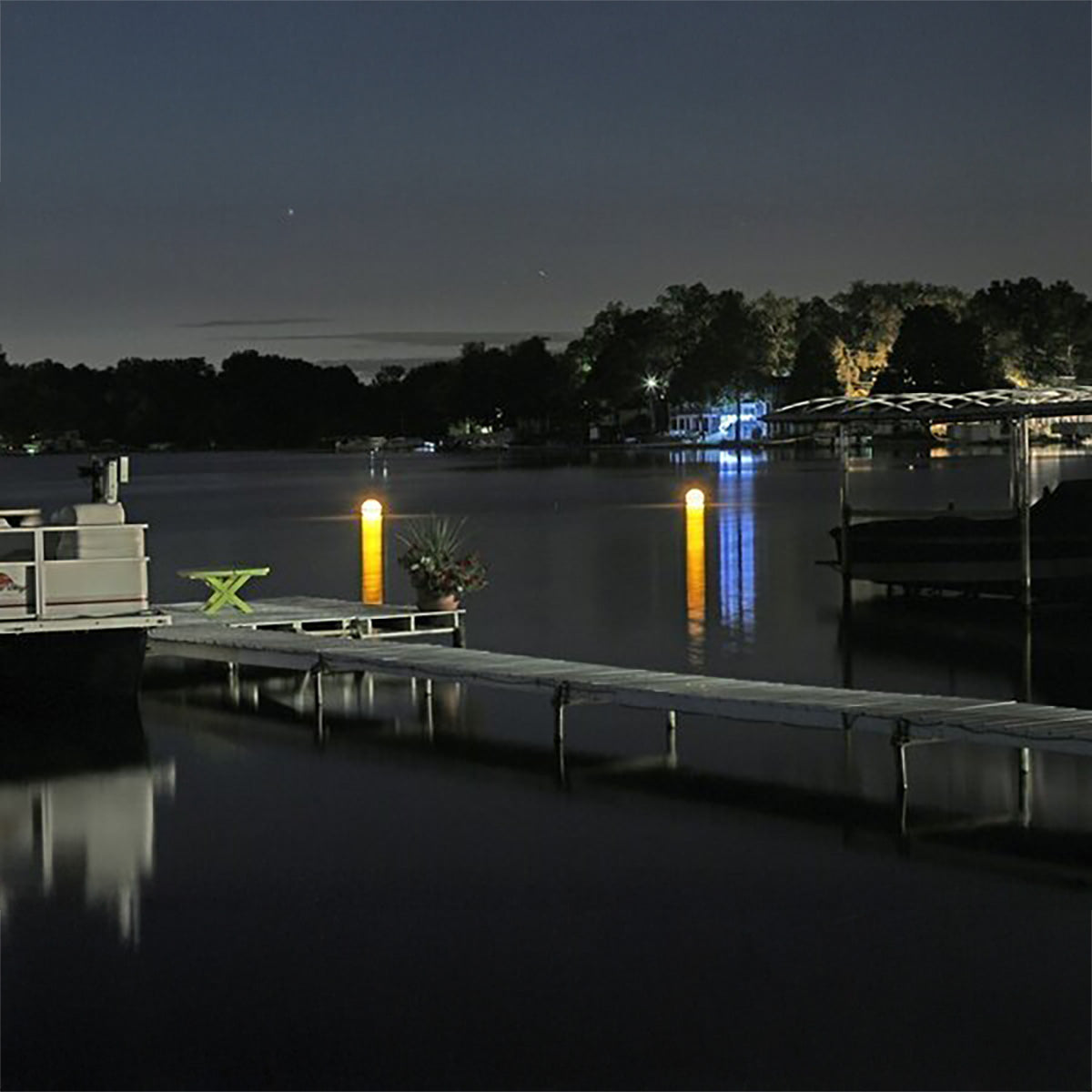 Evening scene at a dock with illuminated lights on a lake.