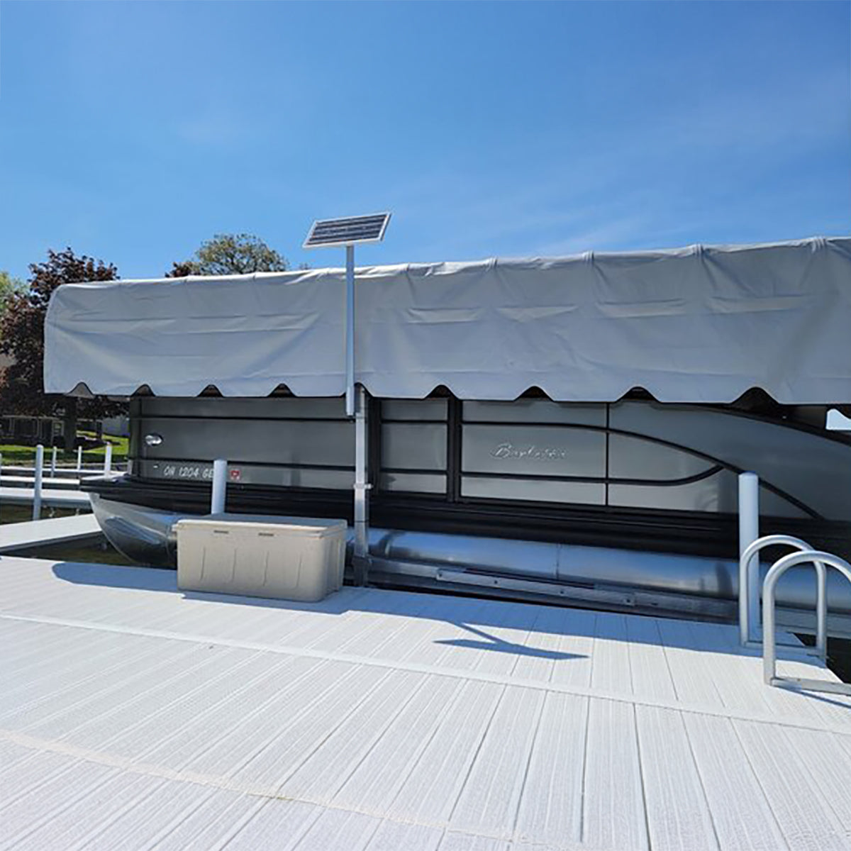 Boat on a dock with a solar panel and storage box in the foreground