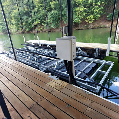 Dock with boat lift mechanism over water, surrounded by greenery