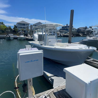 Boat being lifted by a Lake Lifter system at a dock with clear blue sky.