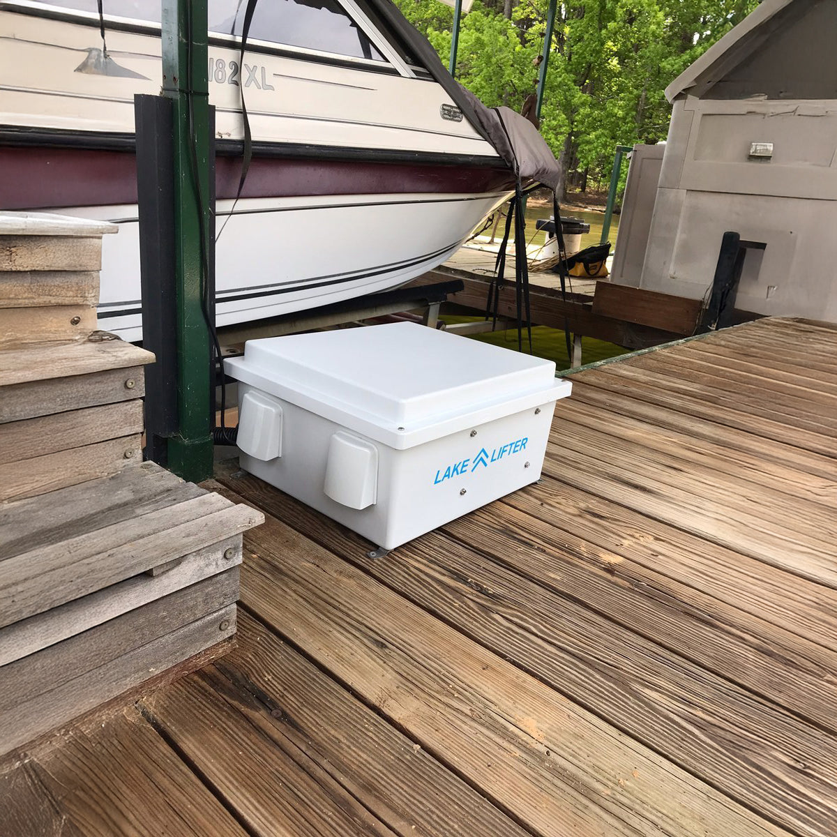 Lake Lifter boat lift system on a wooden dock with a boat in the background.