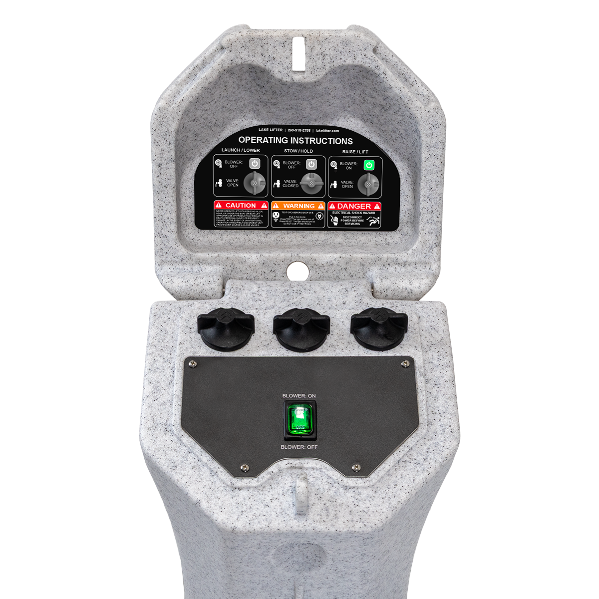 A close-up of a gray speckled industrial control console with an open hinged lid showing an operating instructions panel, three black rotary knobs, a black control faceplate with a green power switch, and a white background.