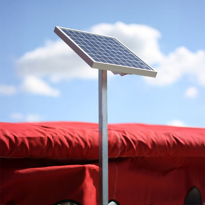 Solar panel on a stand with a red vehicle in the background under a blue sky.