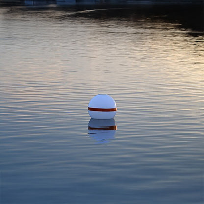White buoy with a red stripe floating on calm water