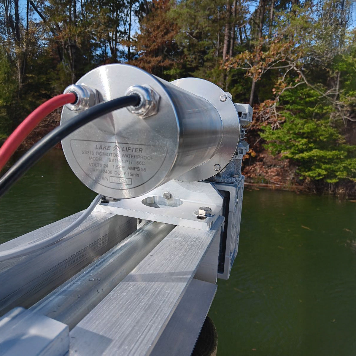 Metal lift mechanism on a dock with water and trees in the background
